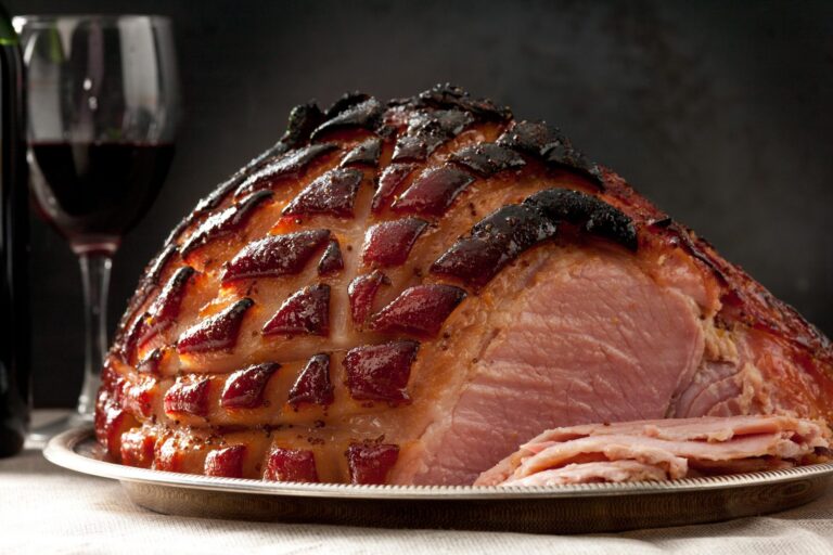 Clove-studded glazed ham sliced on a board