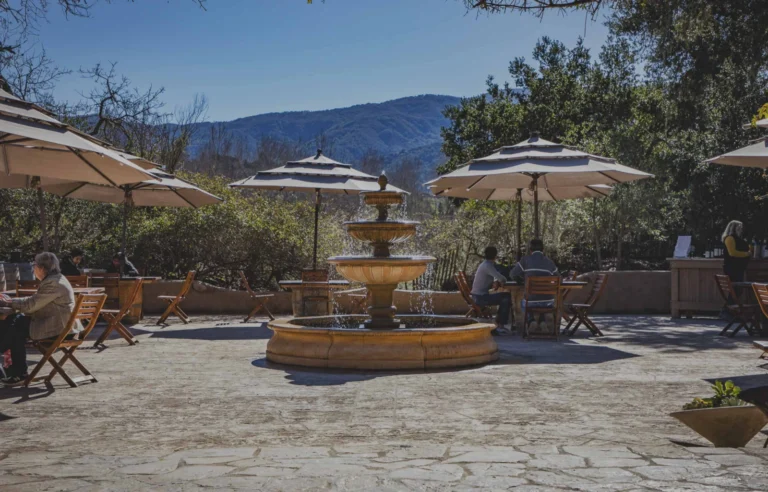 The courtyard fountain at Sunstone, with umbrella-shaded tables and the Santa Ynez hills behind